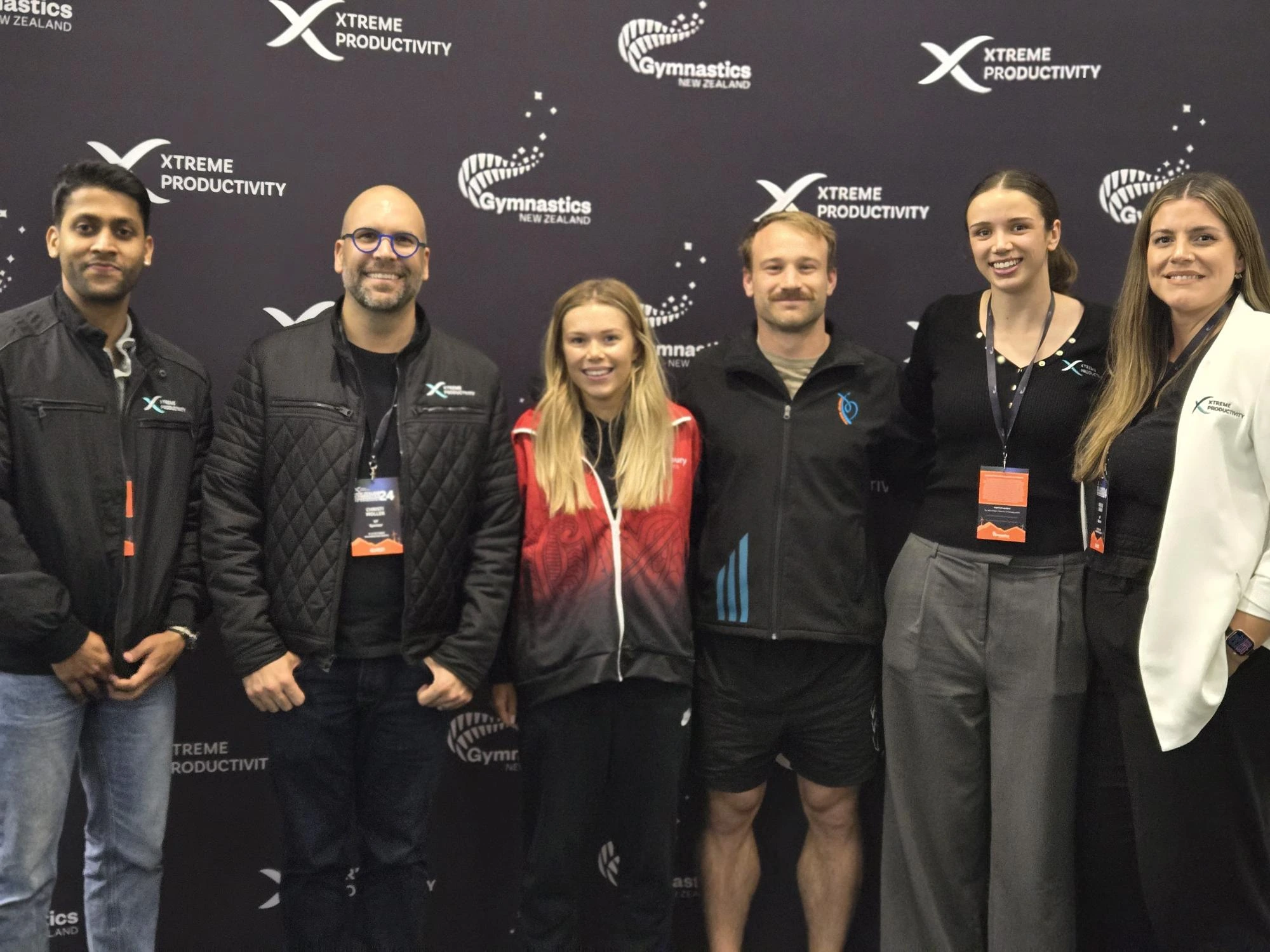 A group of people from XP happily posing for a photo together with Olympians Dylan Schmidt and Maddie Davidsonat the XP Gymnastics Championships 2024, showcasing their excitement and camaraderie